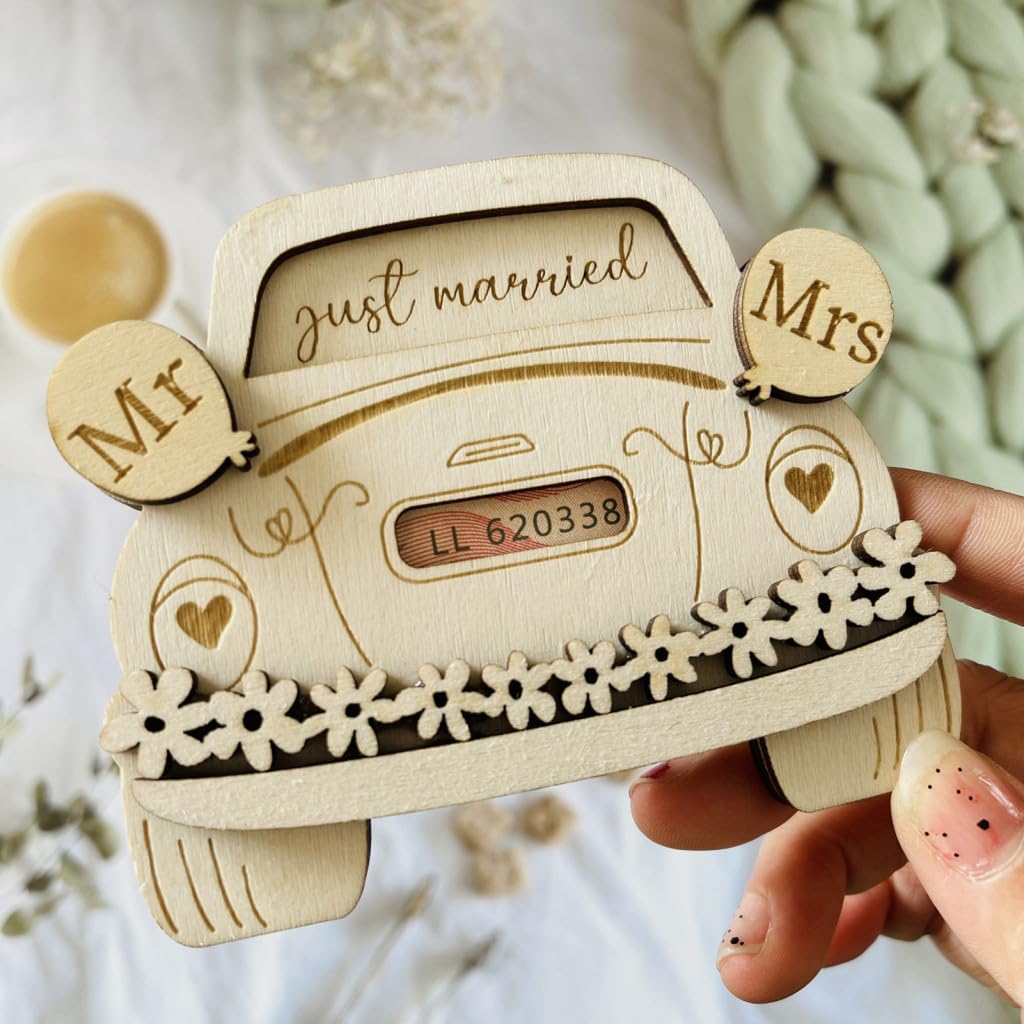Wooden car-shaped ornament with 'just married' and 'Mrs' text, held by a hand.