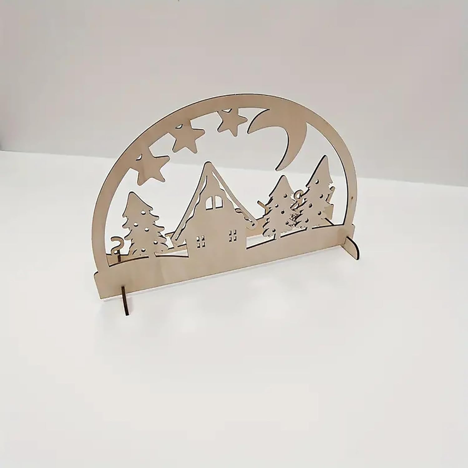 Decorative metal arch with cut-out designs of a house, trees, and stars on a white background
