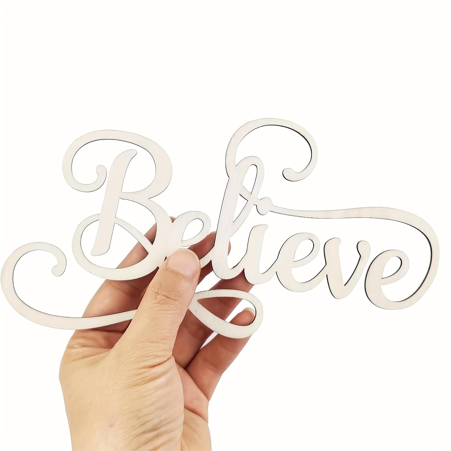 Hand holding a decorative sign with 'Believe' written on it against a white background