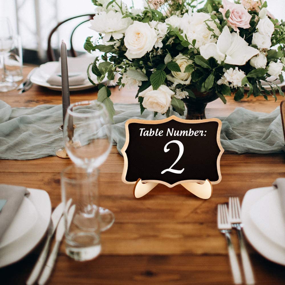 Table setting with floral centerpiece and table number sign on a wooden table.