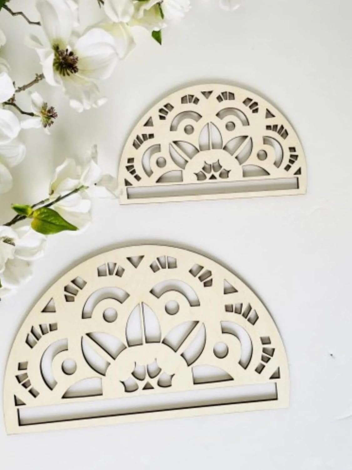Two decorative half-circle wooden items with intricate cut-out patterns on a white background with flowers.