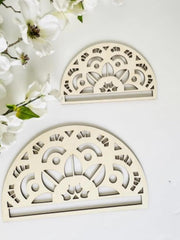 Two decorative half-circle wooden items with intricate cut-out patterns on a white background with flowers.