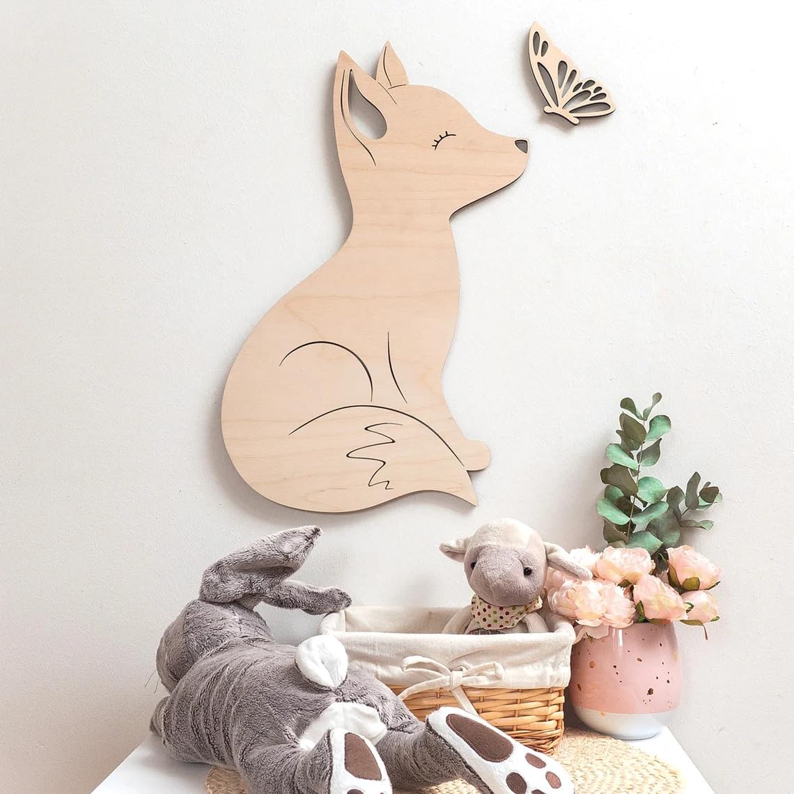 Wooden fox wall decoration in a child's room with toys and plants.