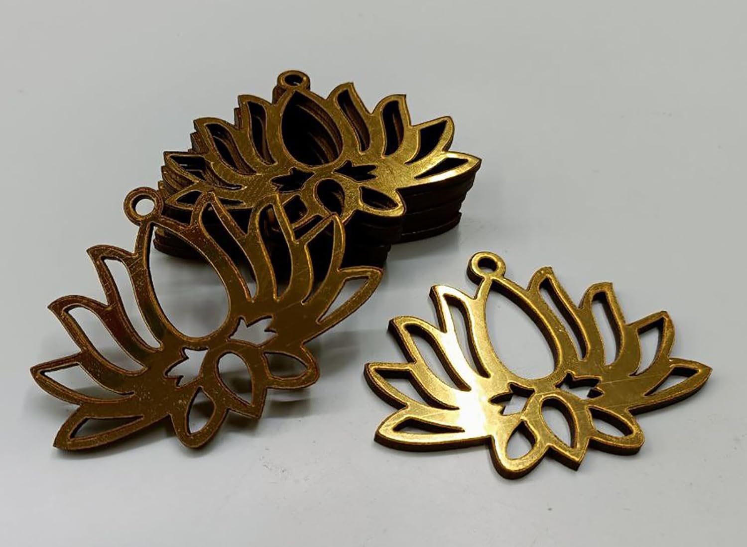 Three gold lotus flower-shaped metal objects on a white background