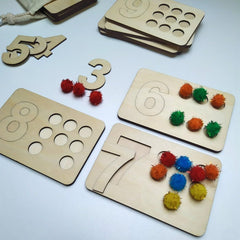 Wooden educational toys with numbers and colorful pom-poms on a light blue background