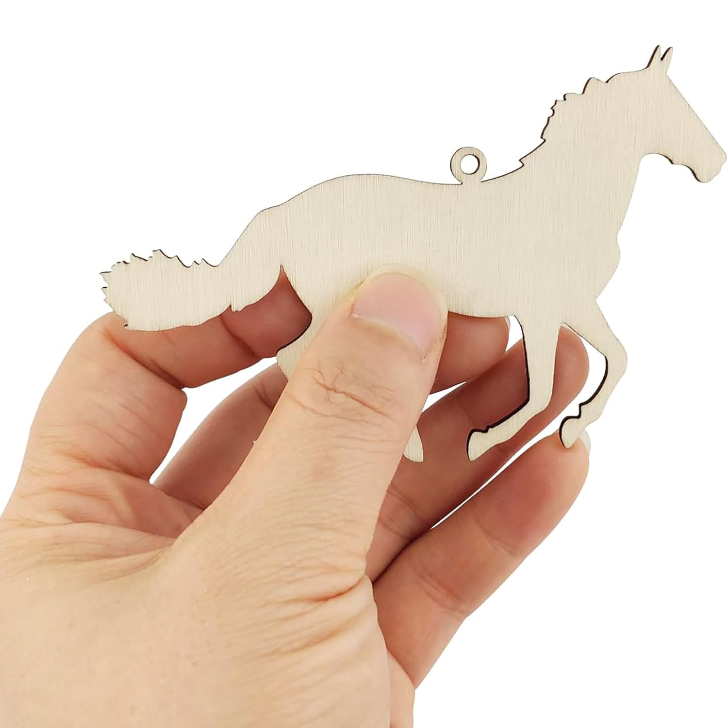 Hand holding a wooden horse-shaped ornament against a white background