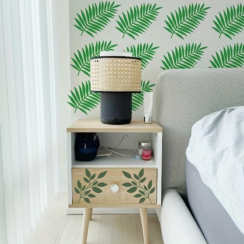 Bedroom with a nightstand featuring leaf designs, a lamp, and decorative items against a wall with green leaf patterns.