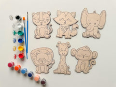 Set of animal-shaped wooden cutouts with paint supplies on a light background