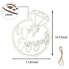Wooden 'We're Engaged' sign with dimensions and a string for hanging on a white background.