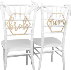 Two white chairs with 'bride' and 'groom' signs on a white background