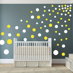 Nursery room with a crib and polka dot wall decors on a gray wall.