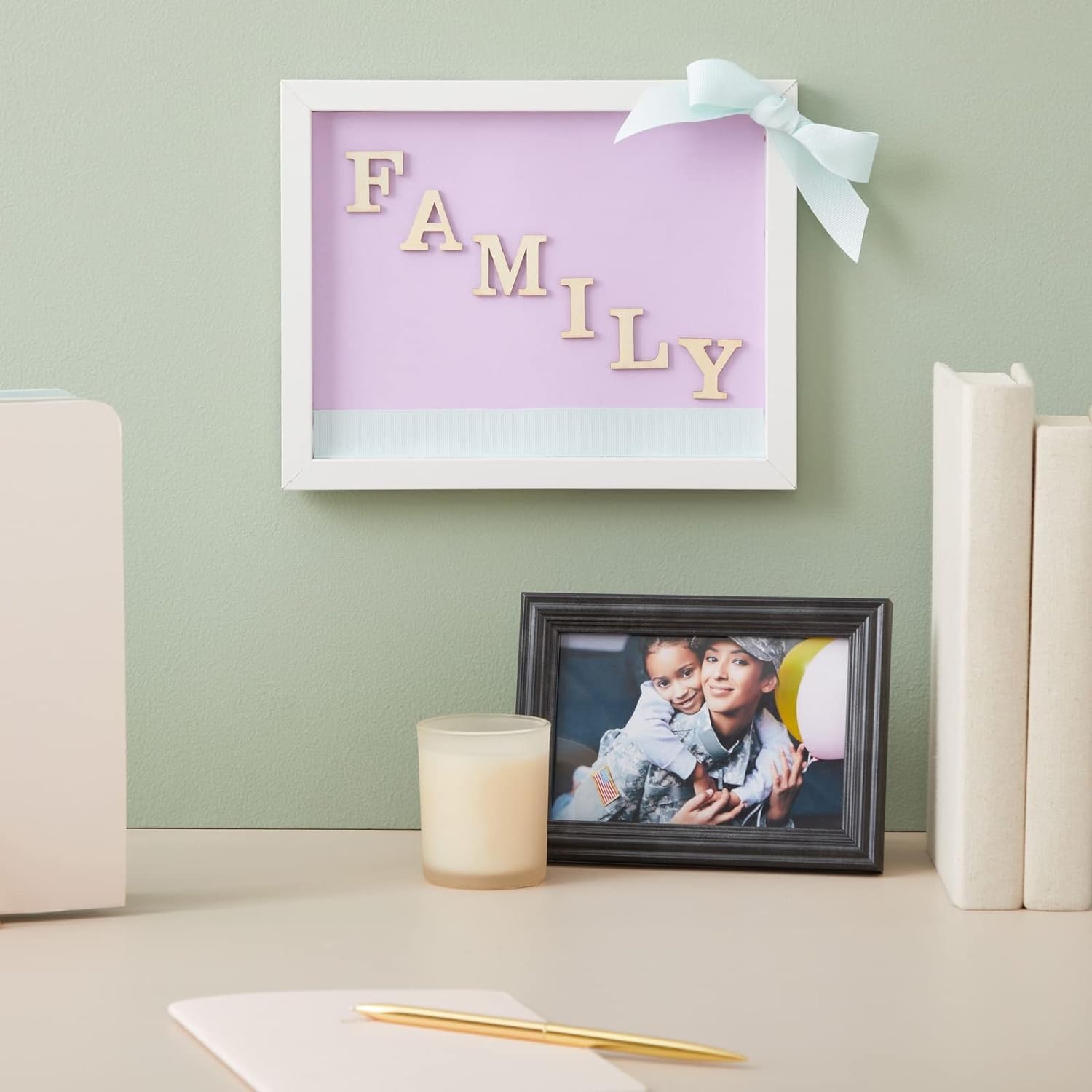 Decorative wall art with 'FAMILY' letters on a purple background, placed above a framed photo of two people.