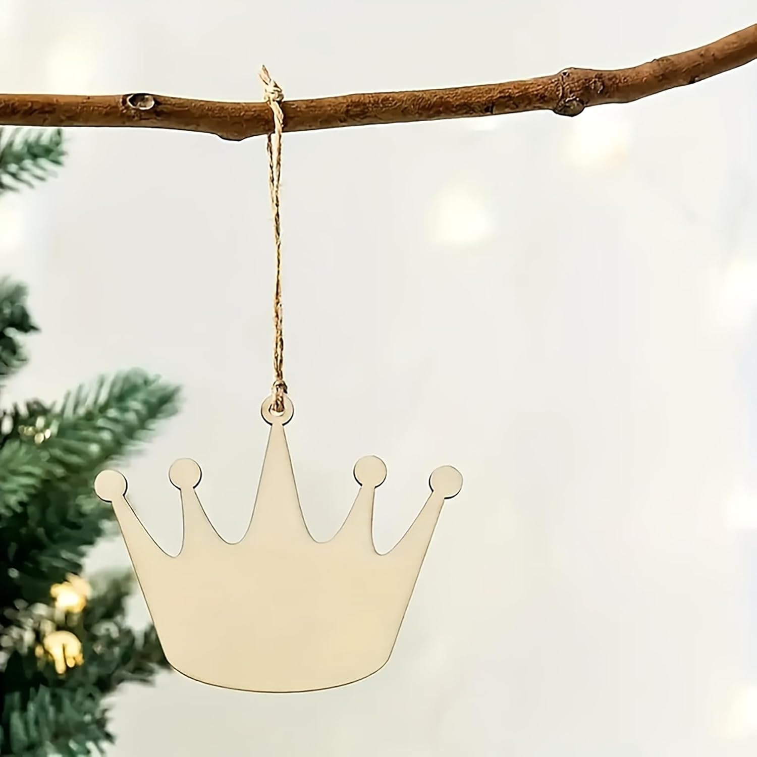 Gold crown-shaped ornament hanging on a branch with a blurred Christmas tree background