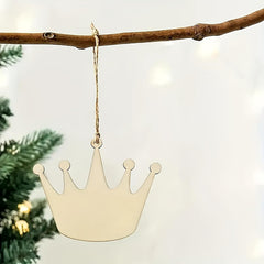Gold crown-shaped ornament hanging on a branch with a blurred Christmas tree background