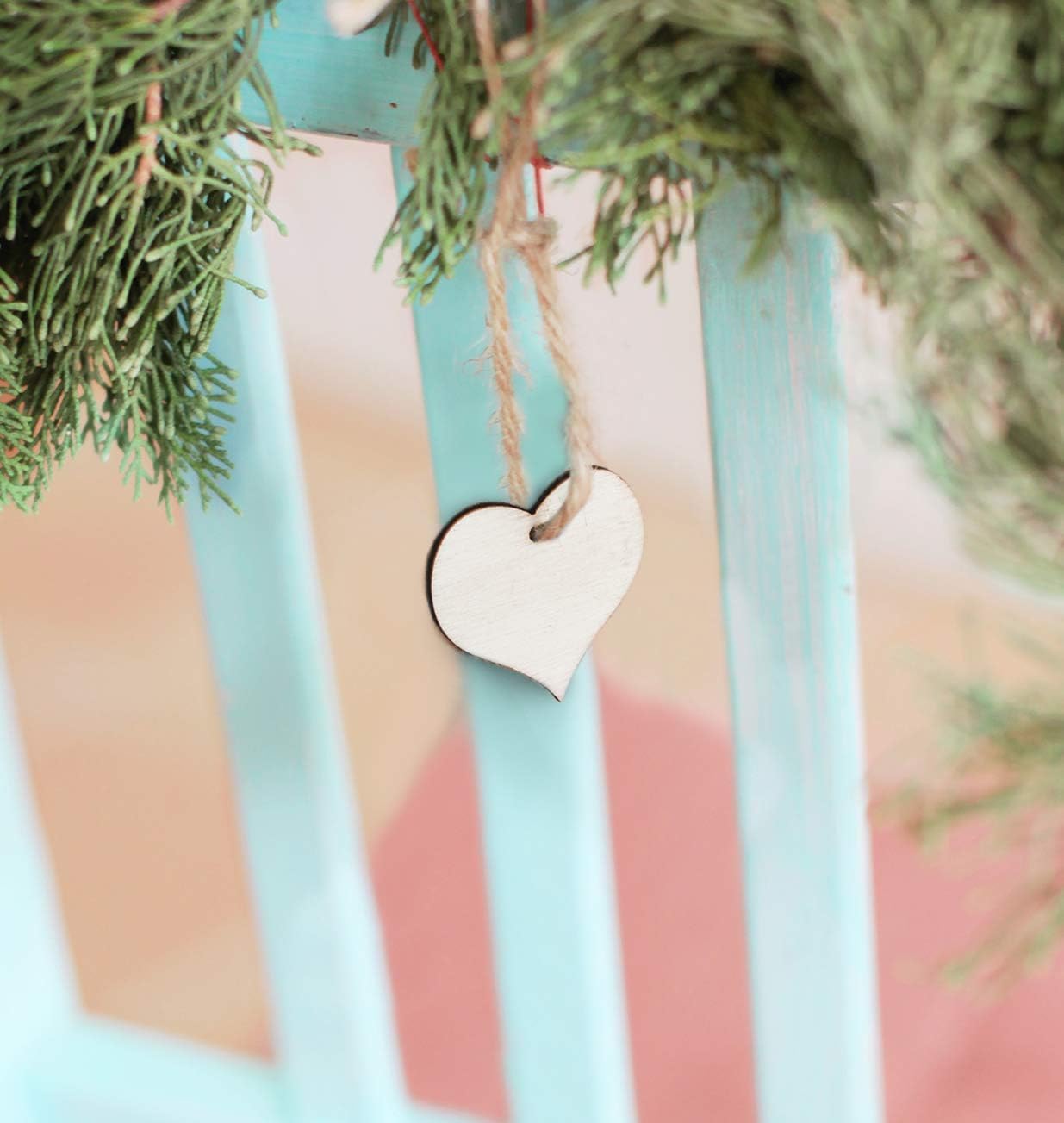 Heart-shaped ornament hanging from a branch with a colorful striped background