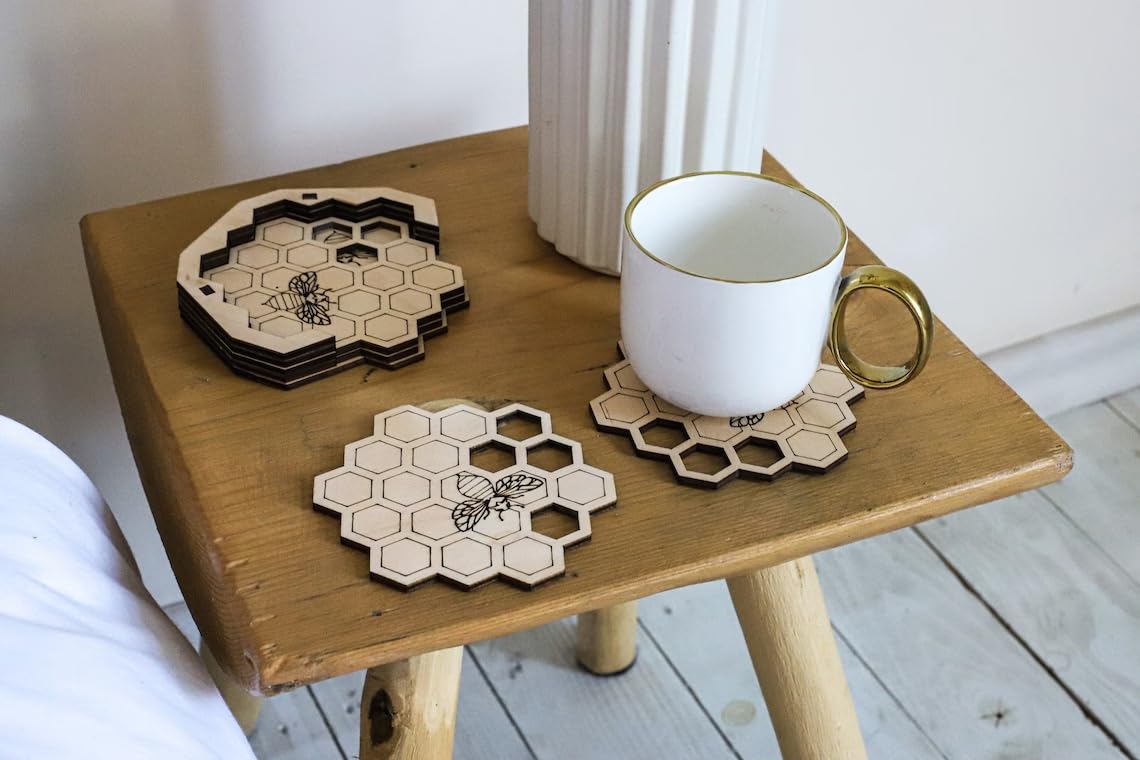 Wooden table with hexagonal coasters and a white mug on a light wooden floor.