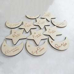 Wooden moon and star-shaped milestone markers with engraved text on a light gray background.