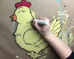 Hand coloring a cartoon chicken with a marker on a brown background