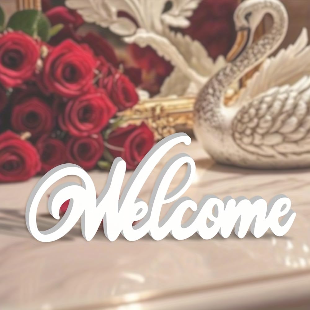 Decorative 'Welcome' sign with red roses and a swan figurine on a reflective surface.