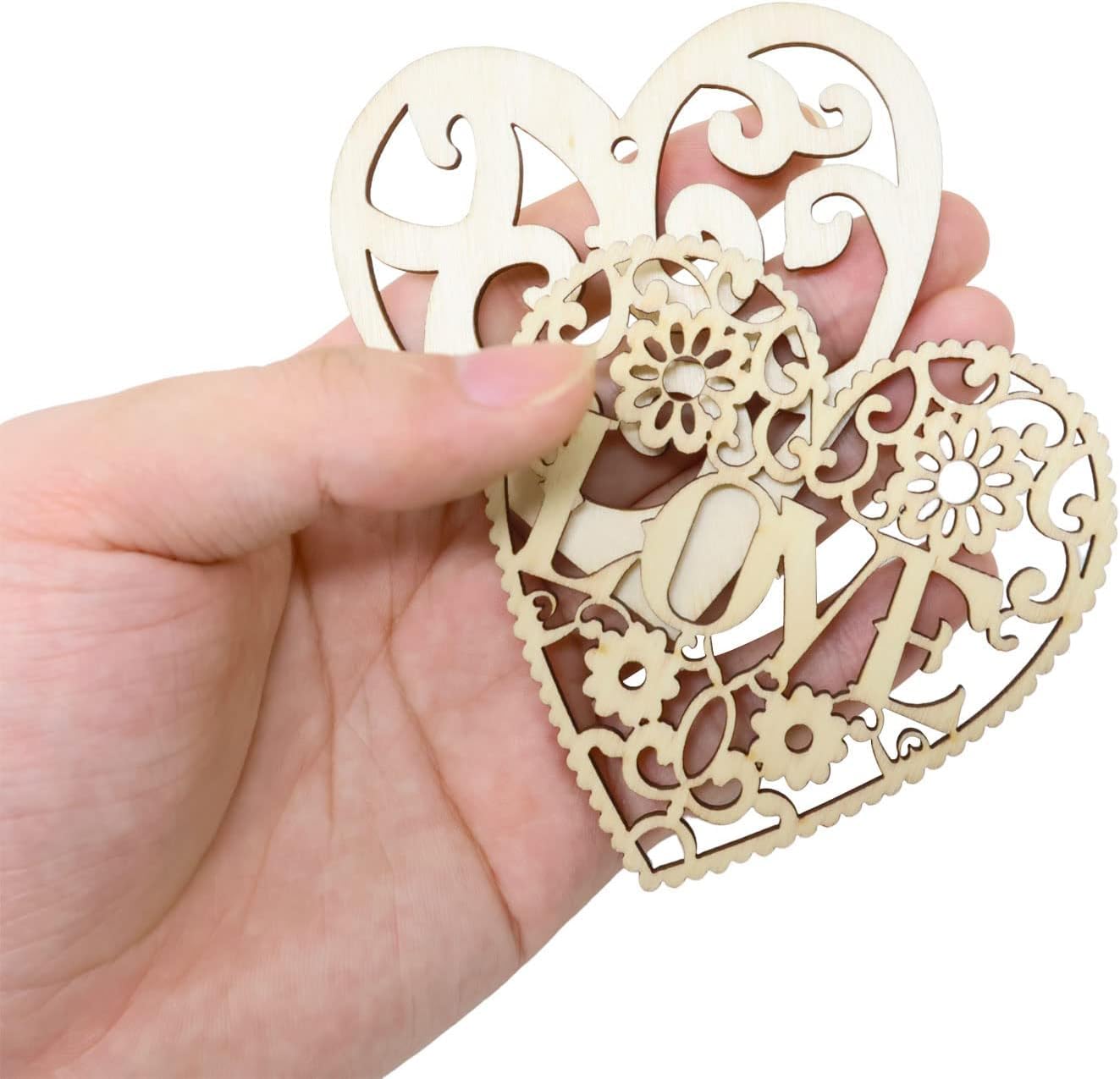 Decorative wooden heart-shaped ornament with 'LOVE' engraving held in a hand.