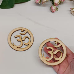 Wooden om symbol coasters on a light surface with a hand holding one coaster.