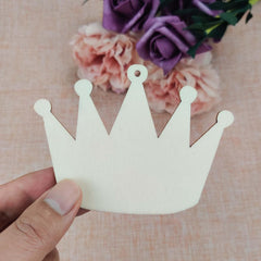 White paper crown held by a hand with flowers in the background