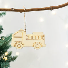 Wooden toy truck ornament hanging on a branch with a blurred Christmas tree background