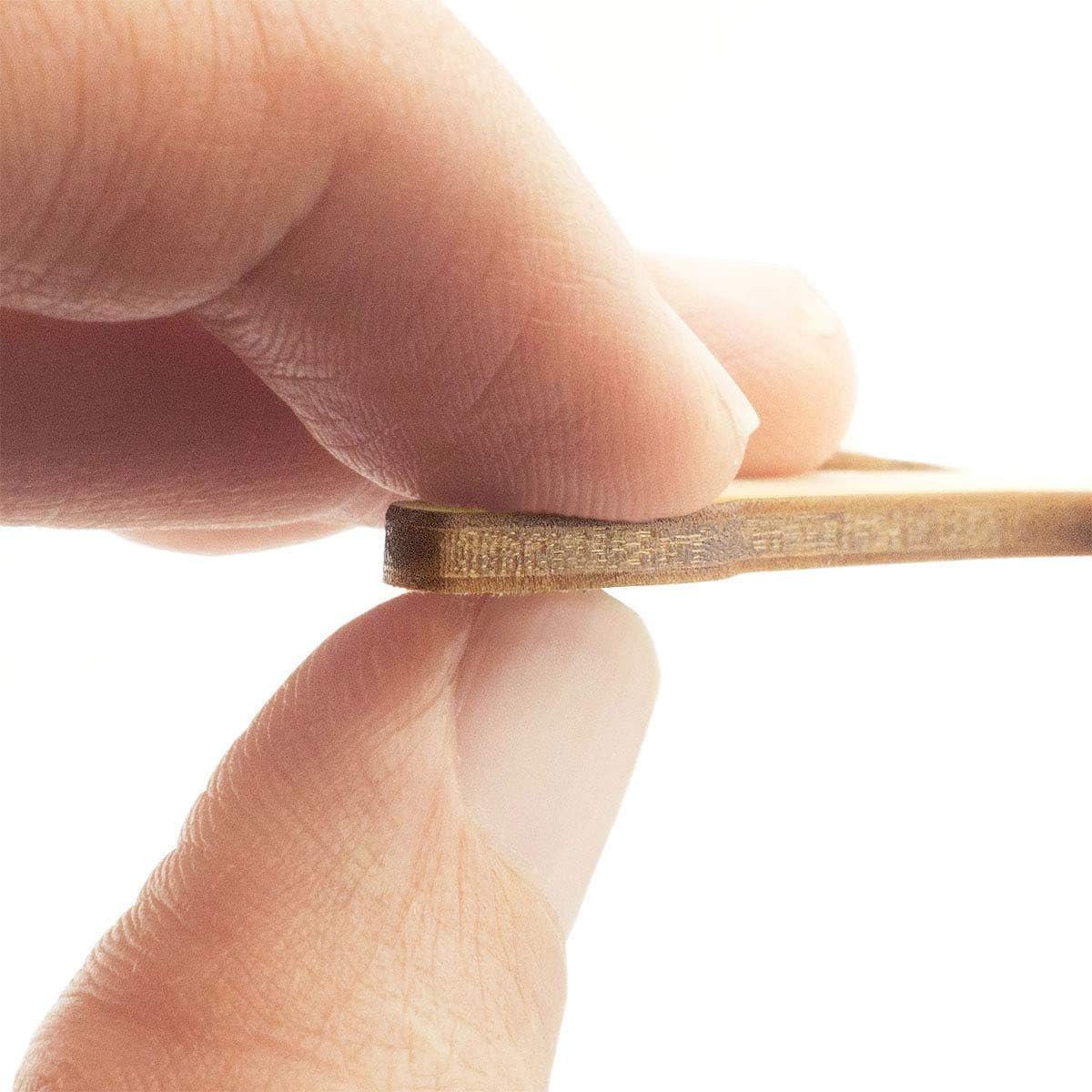 Close-up of a hand holding a thin, flexible gold strip against a white background