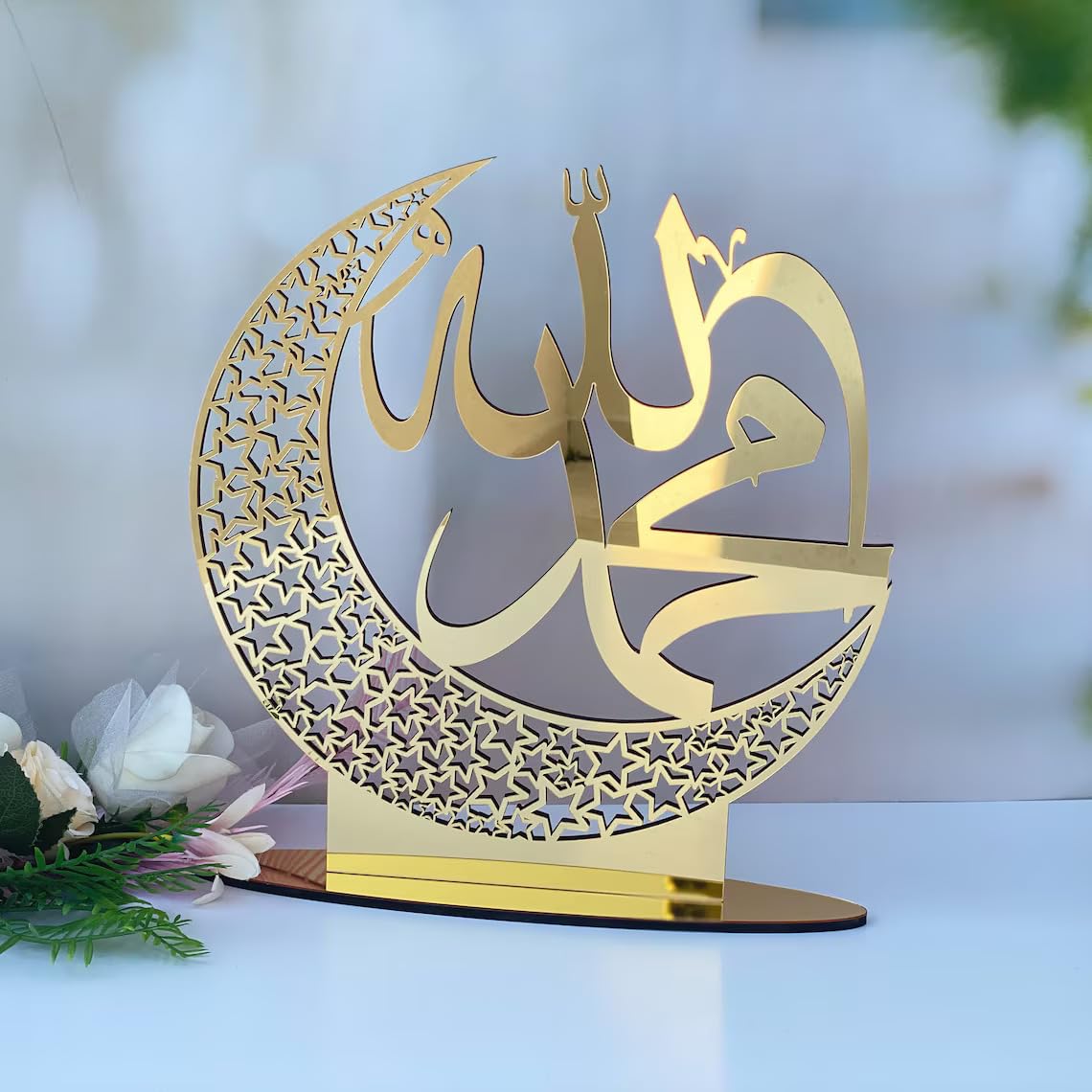 Decorative gold metal piece with Arabic calligraphy on a white surface