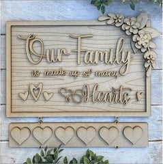 Decorative wooden sign with 'Our Family is made up of many Hearts' text and heart designs on a light background.