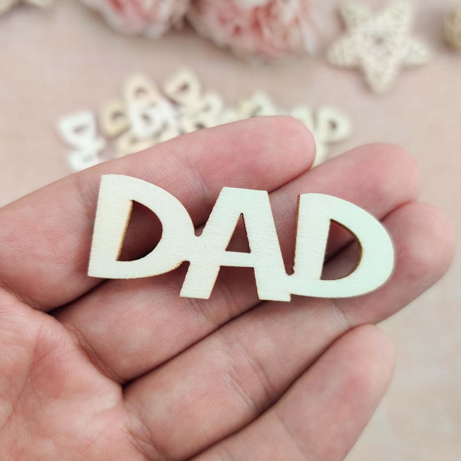 Wooden letters spelling 'DAD' held in a hand with a soft, blurred background.