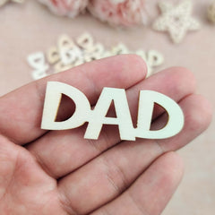 Wooden letters spelling 'DAD' held in a hand with a soft, blurred background.