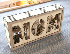 Wooden decorative box with cut-out letters spelling 'DAD' on a wooden surface.