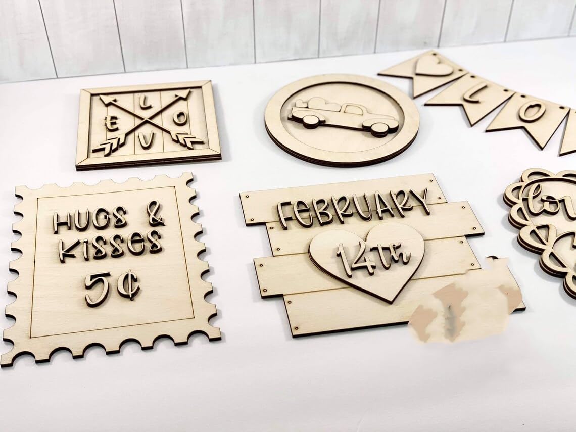 Collection of wooden decorative signs with various designs on a white surface.