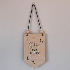 Wooden sign with 'Shhh... Baby Sleeping' text and decorative elements on a plain background