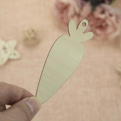 Hand holding a beige carrot-shaped cutout against a blurred floral background