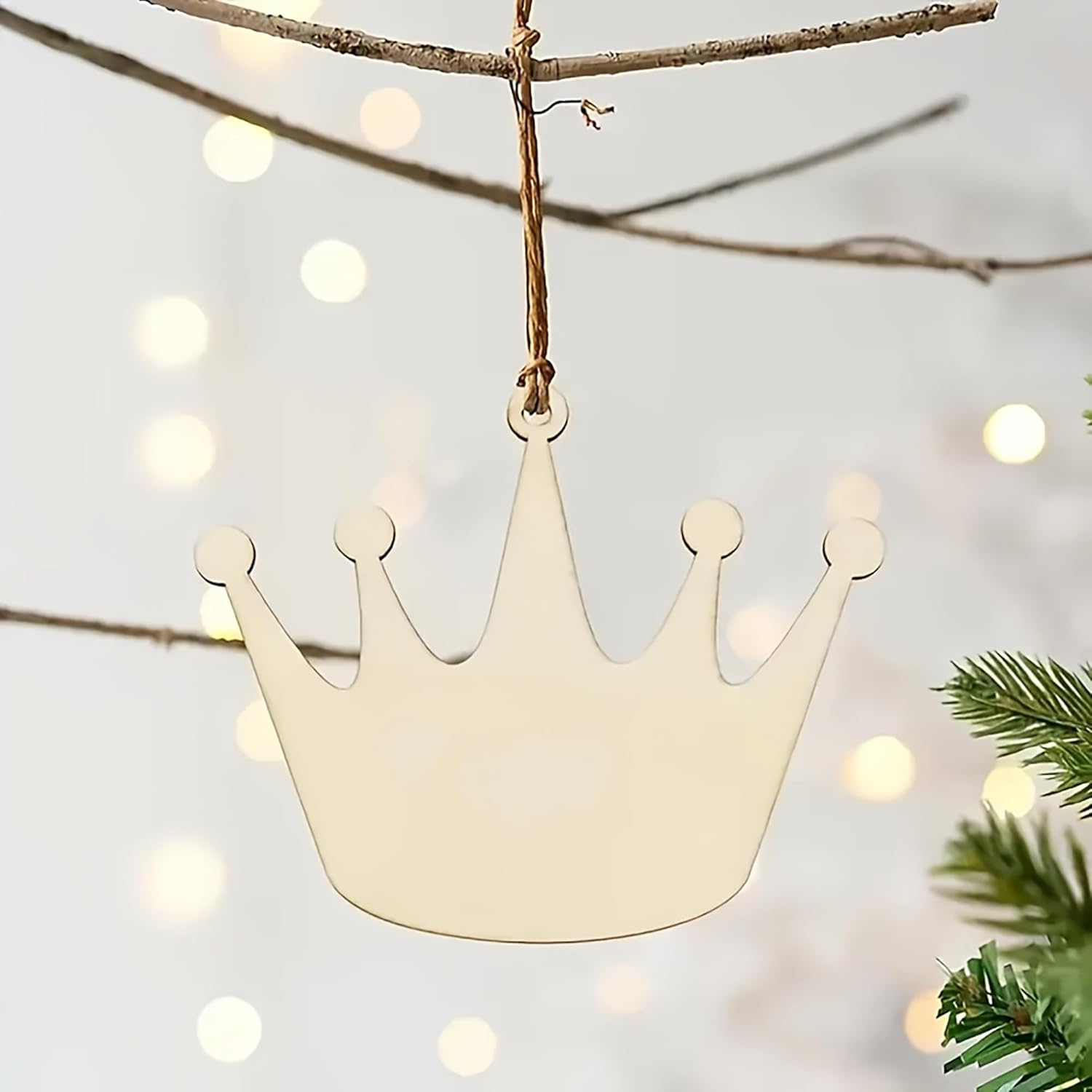 Crown-shaped ornament hanging on a branch with a blurred light background