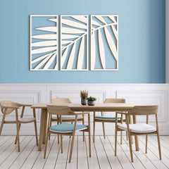 Dining room with wooden table and chairs against a blue wall with decorative leaf art.