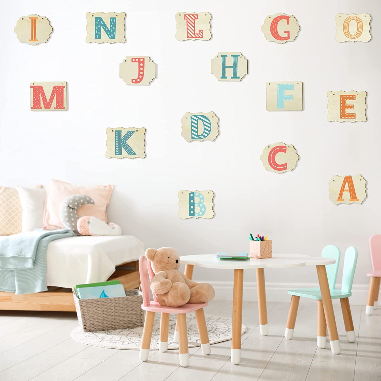 Children's room with colorful alphabet letters on the wall, a teddy bear on a chair, and a small table.
