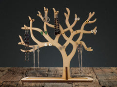 Wooden earring tree with various earrings on a rustic wooden surface and dark background