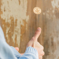 Hand giving a thumbs-up gesture with a blurred wooden background