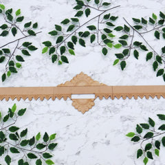 Decorative wooden border with intricate design on a white marble background with green leaf patterns.