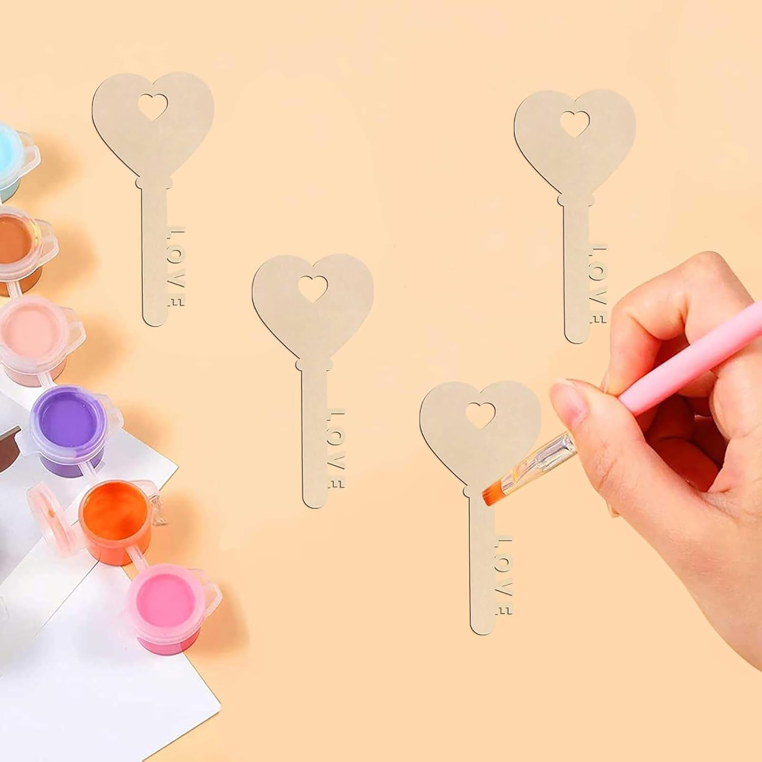 Person painting heart-shaped key templates with paint on a beige background