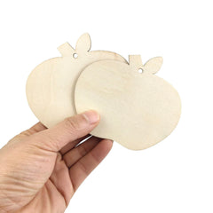 Hand holding two wooden pumpkin shapes against a white background