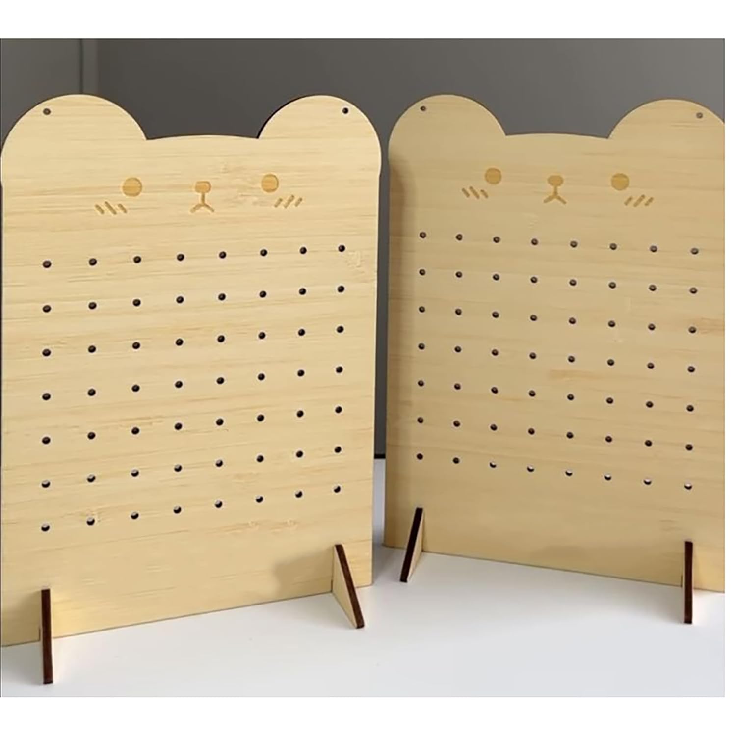 Two wooden pegboards with cat face designs on a plain background