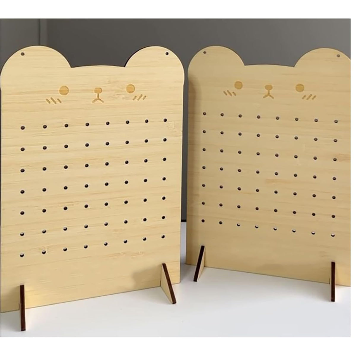 Two wooden pegboards with cat face designs on a plain background