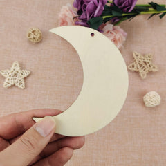 Hand holding a wooden crescent moon ornament on a decorative background with flowers and stars.
