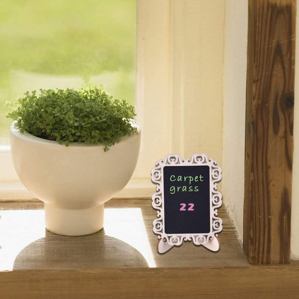 Small potted plant next to a decorative chalkboard on a wooden surface with a blurred background