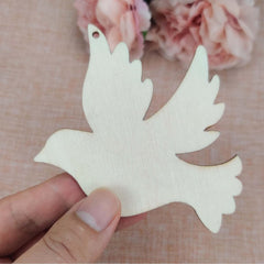 Wooden dove ornament held by a hand with a soft pink floral background