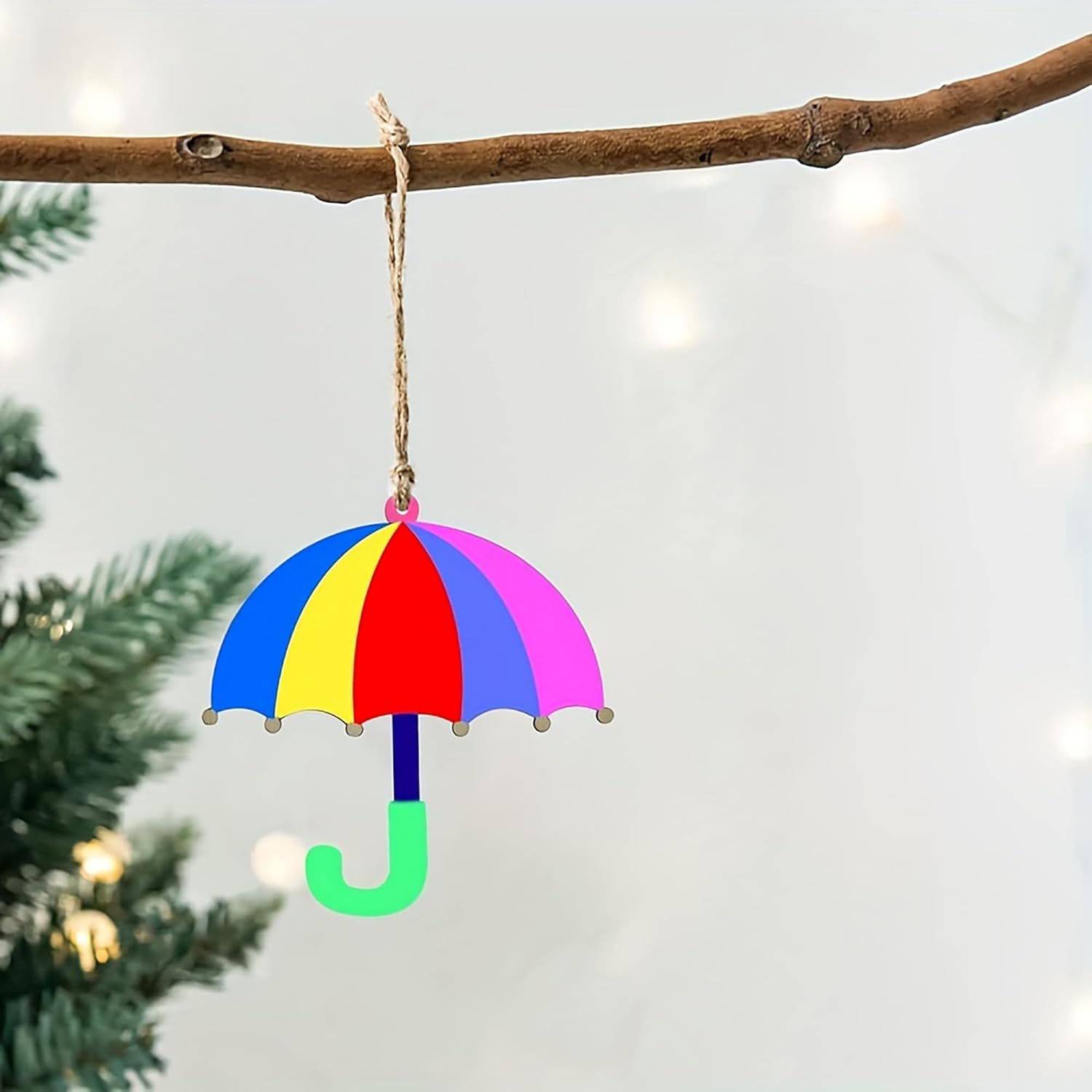 Colorful umbrella ornament hanging on a branch with a blurred Christmas tree background